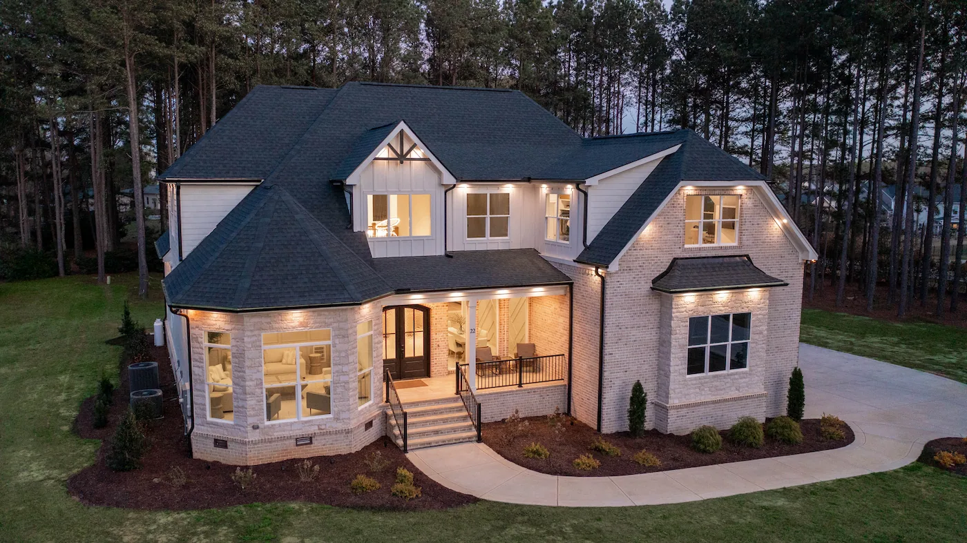 Large modern house with evening lights and trees.