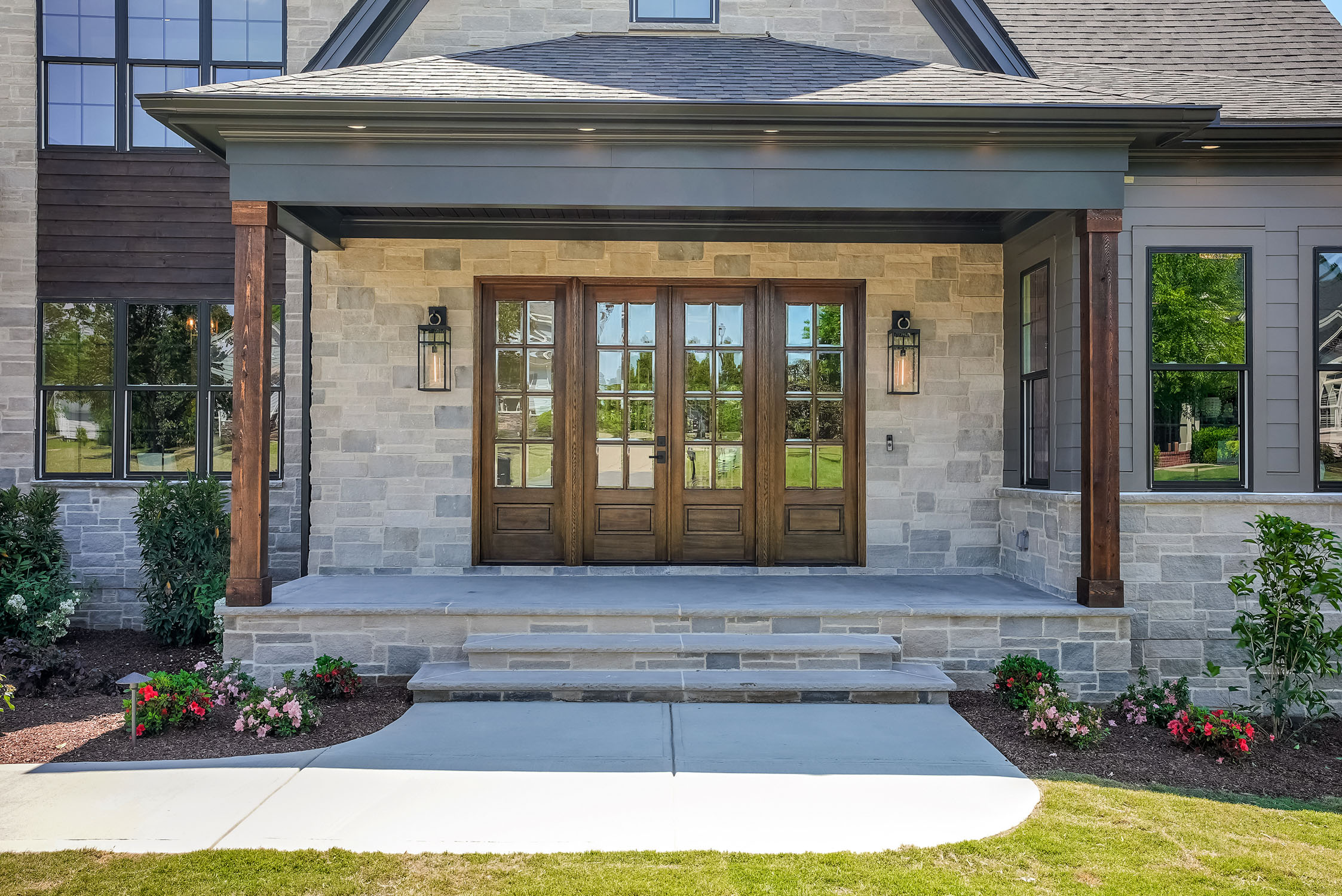 Modern stone home entrance with wooden double doors