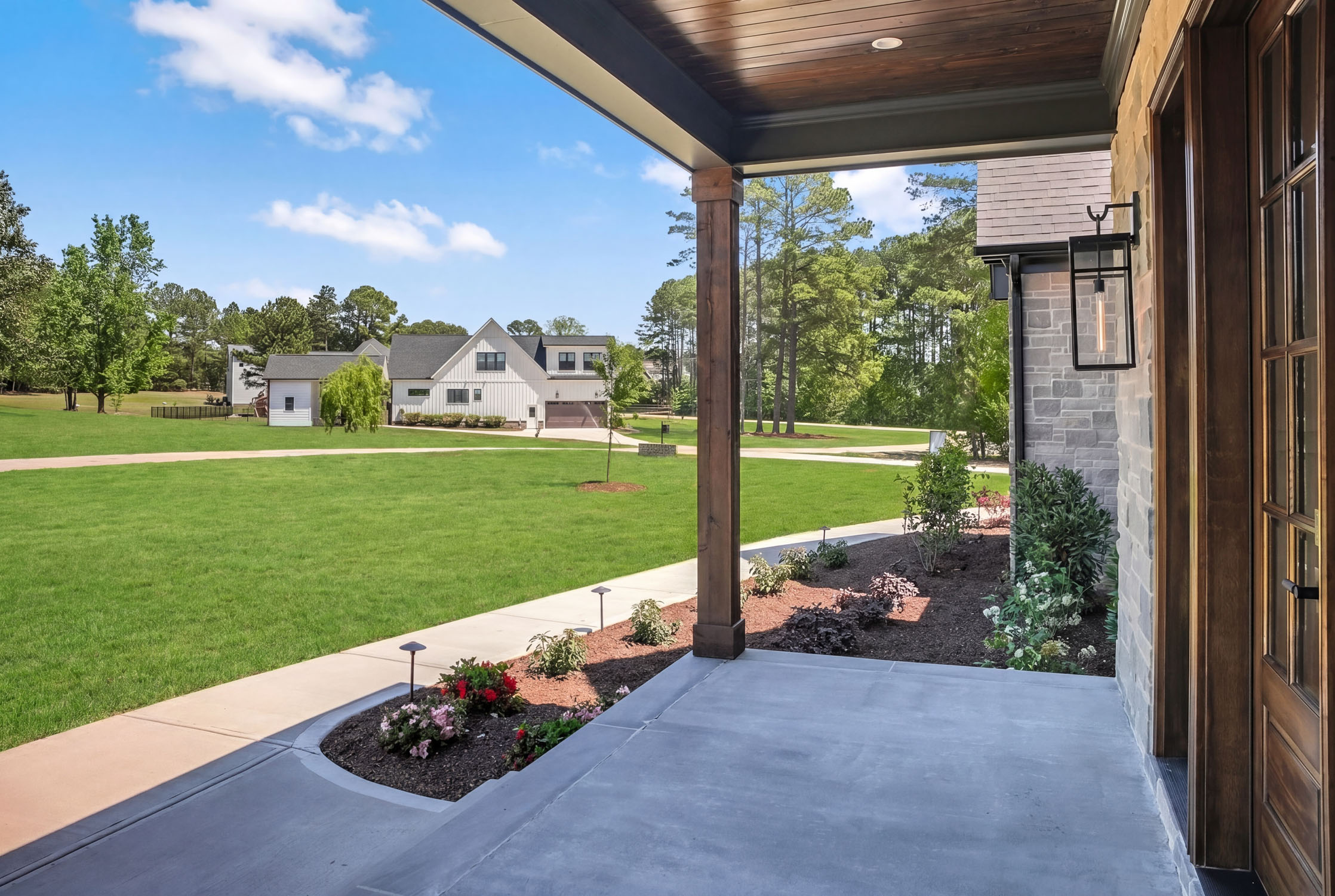 View from covered porch overlooking landscaped suburban lawn