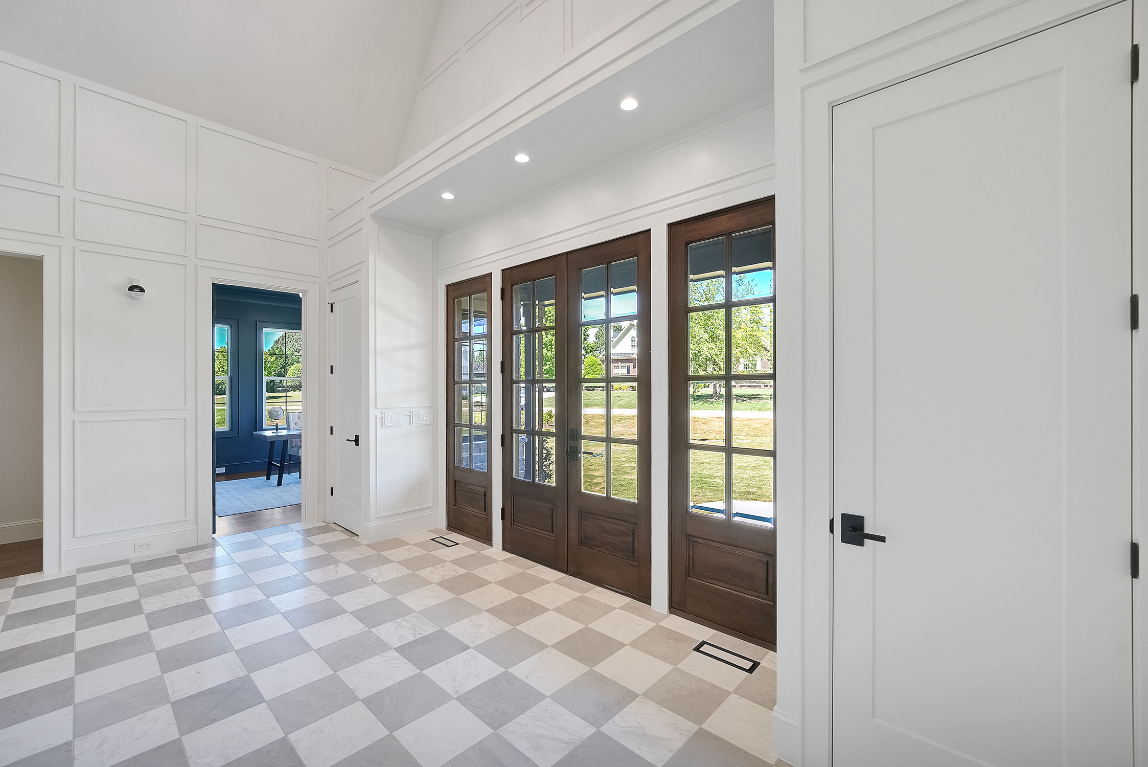 Bright entryway with checkered tile and wooden doors