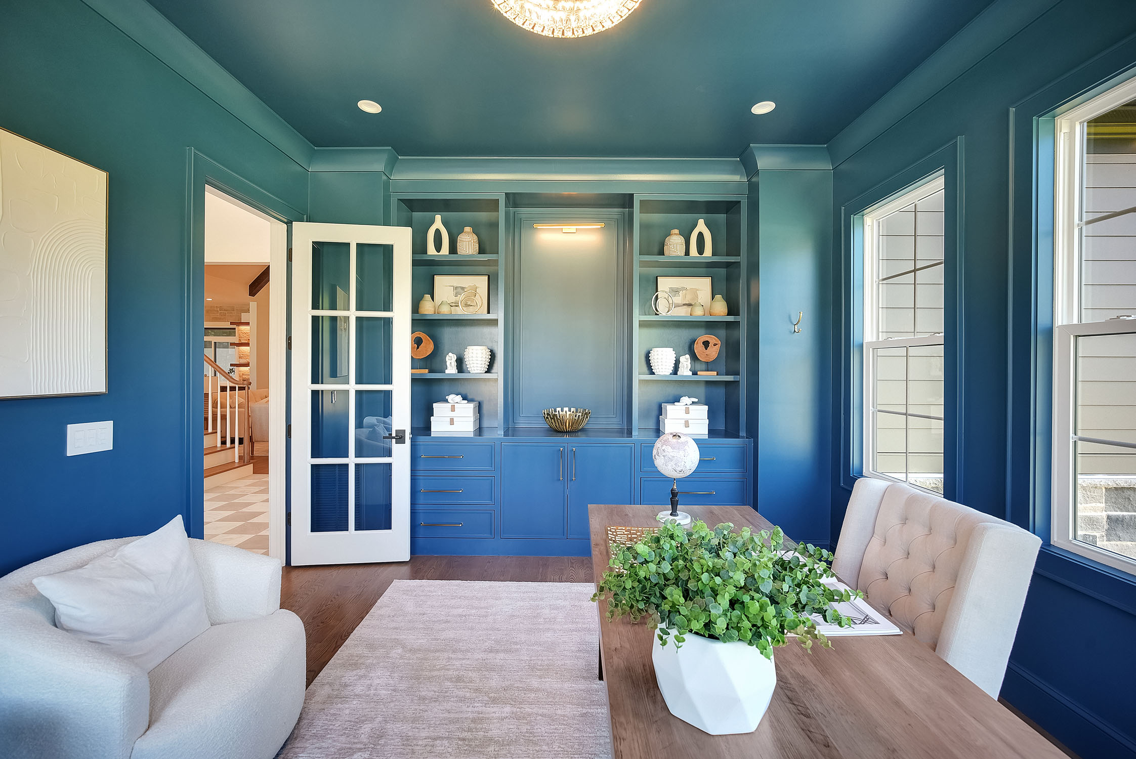 Blue home office with built-in shelves and wooden desk globe