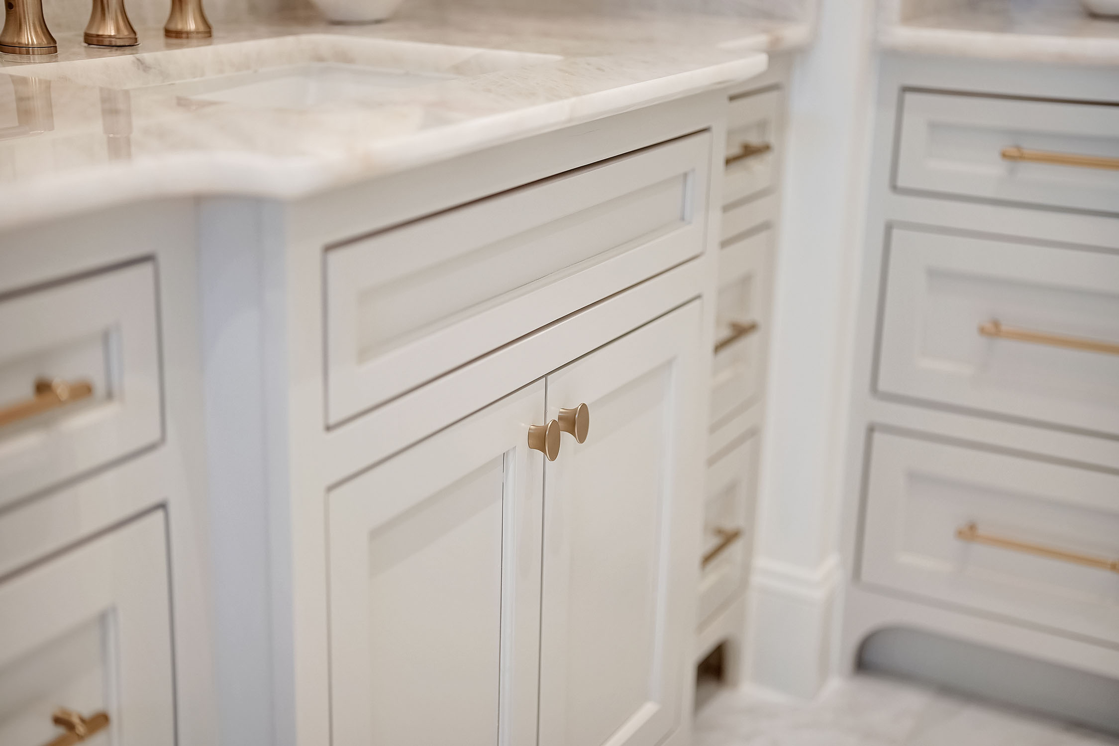 White shaker cabinets with brass hardware and marble countertop