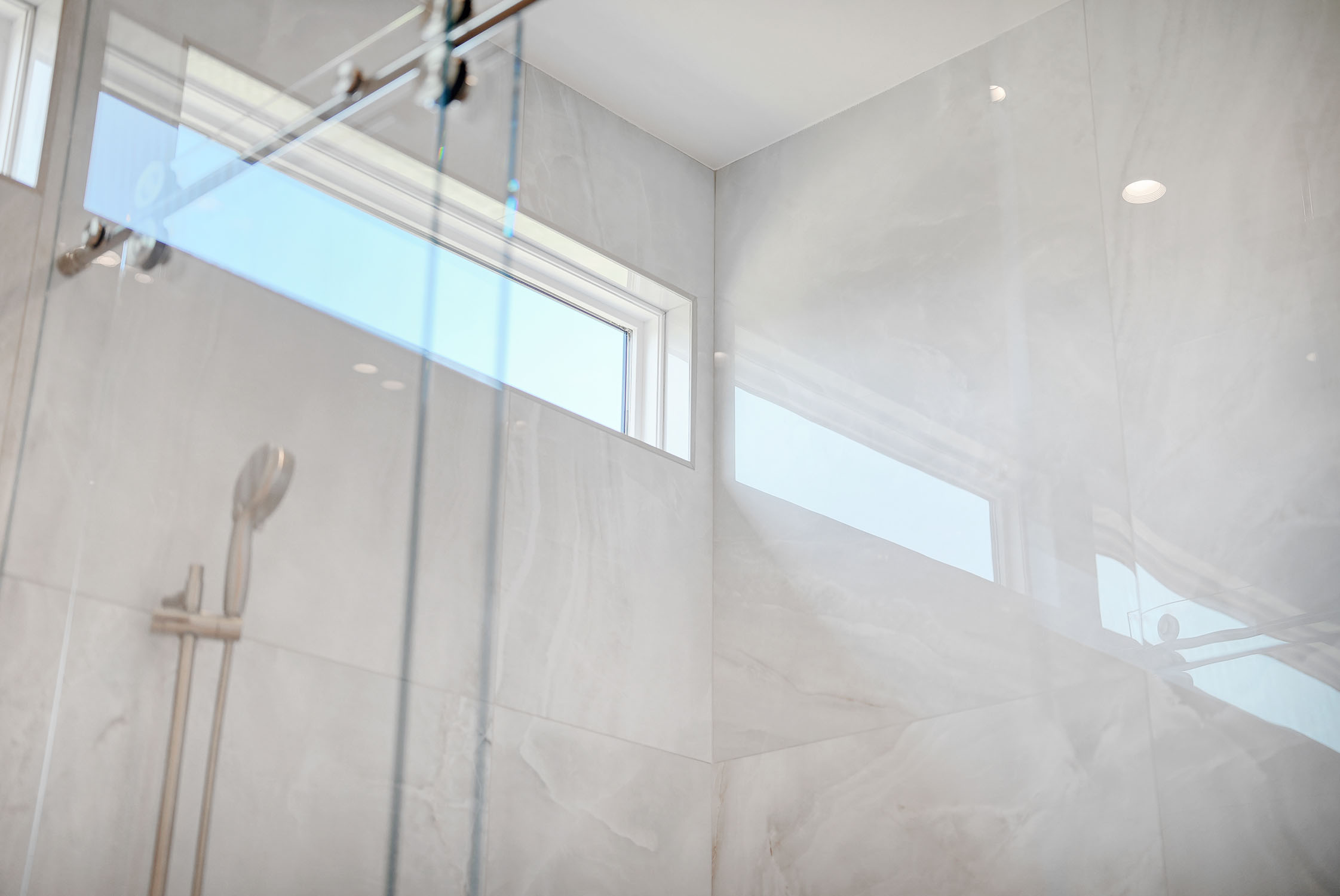 Modern glass shower with marble tile walls
