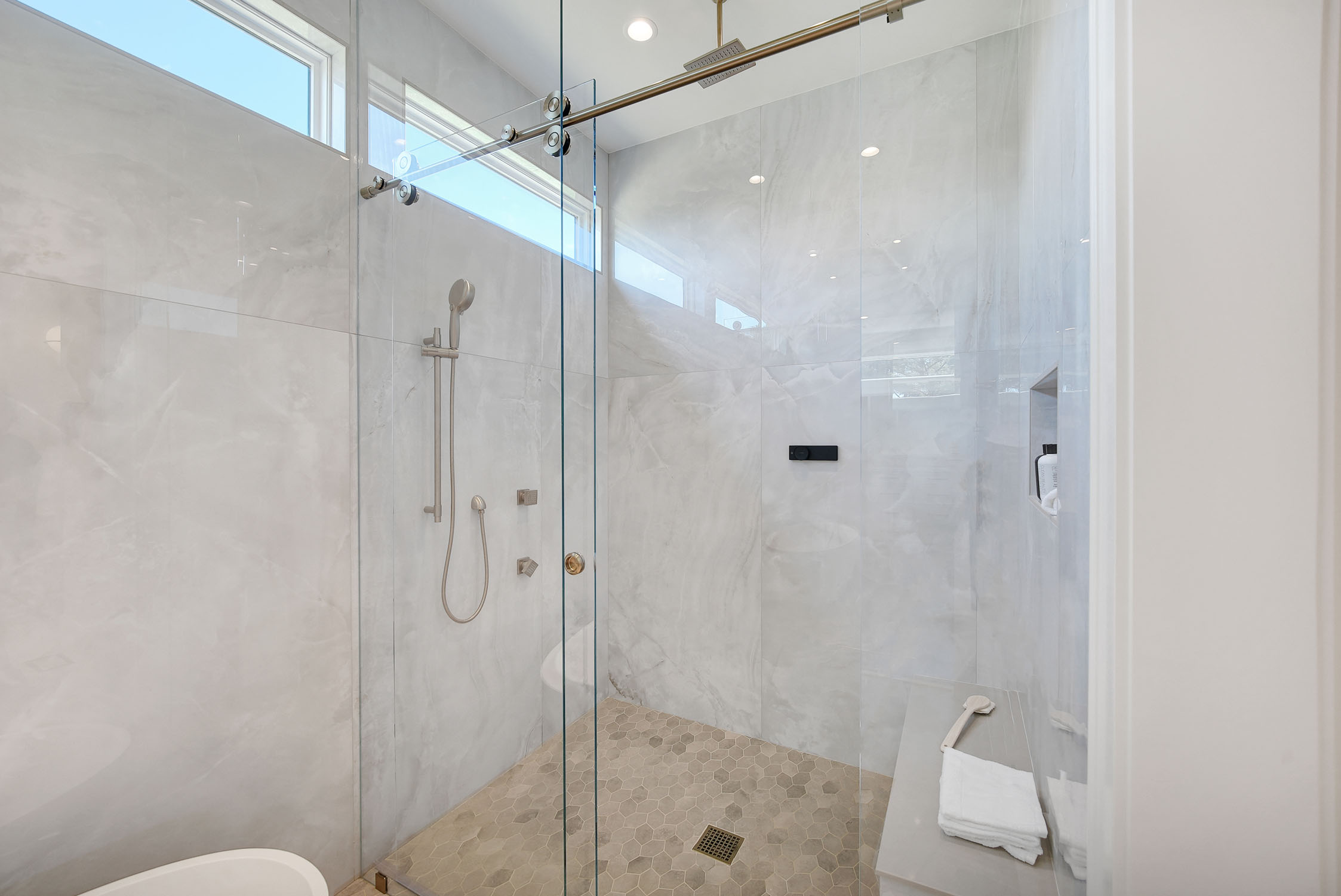 Modern glass walk-in shower with marble tiles