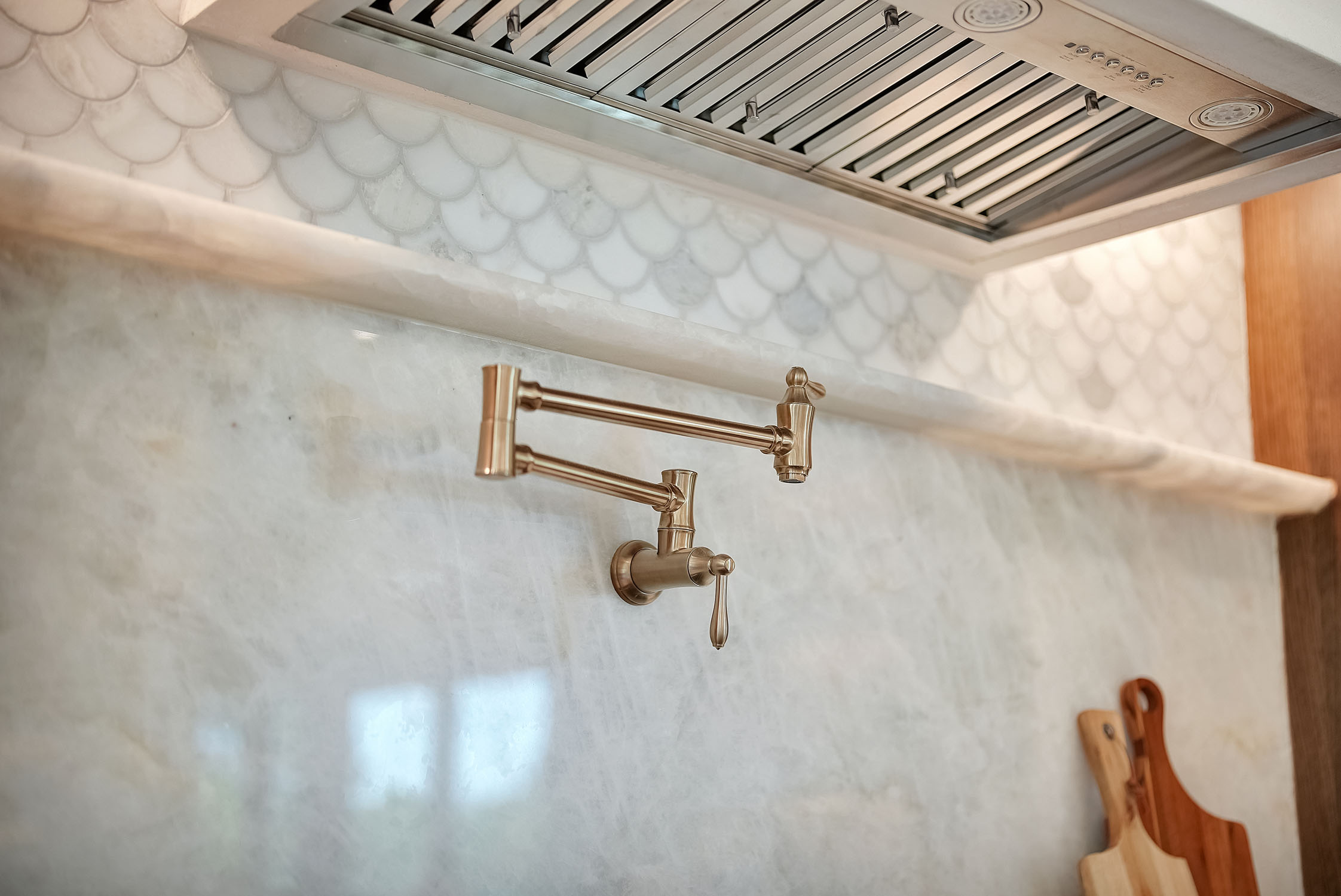 Brass pot filler faucet over marble backsplash