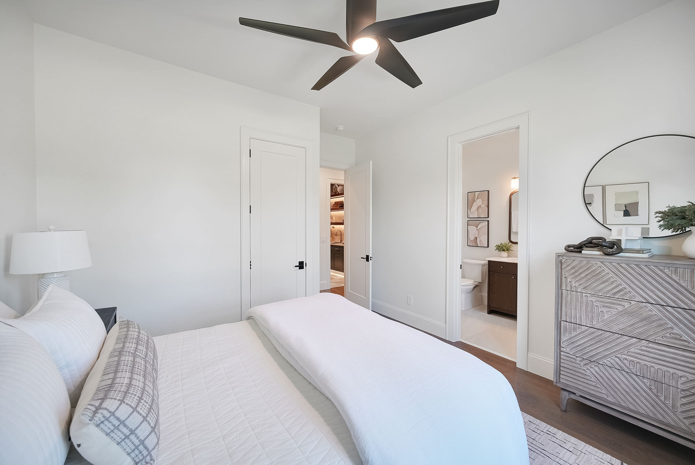 Modern white bedroom with ceiling fan and ensuite bathroom