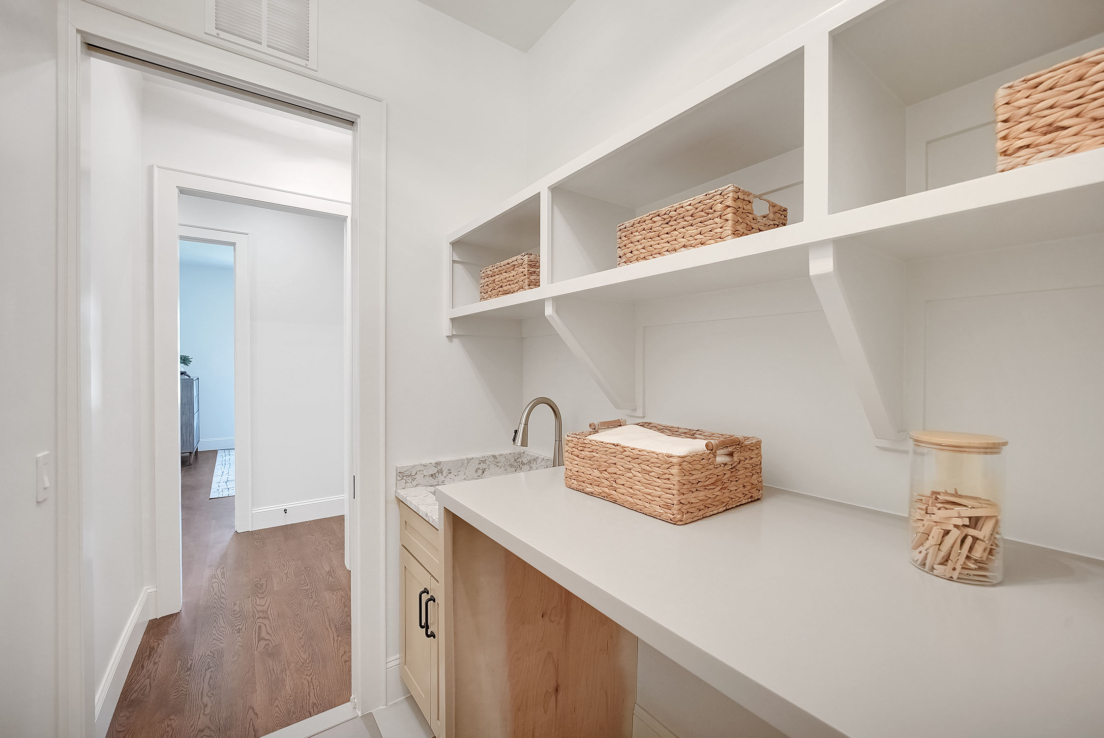 Bright white laundry room with shelves and baskets