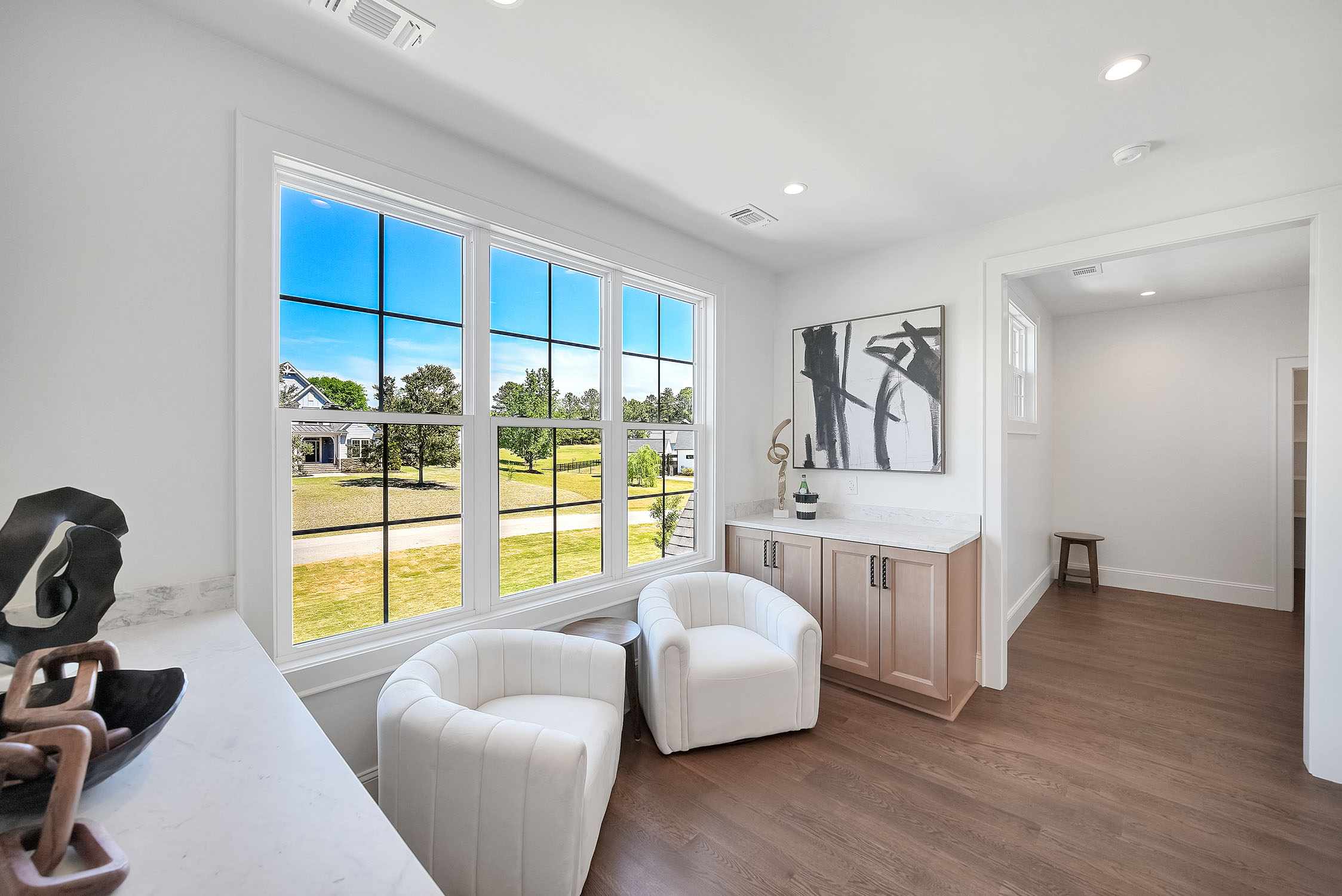 Bright sitting area with large windows and white chairs