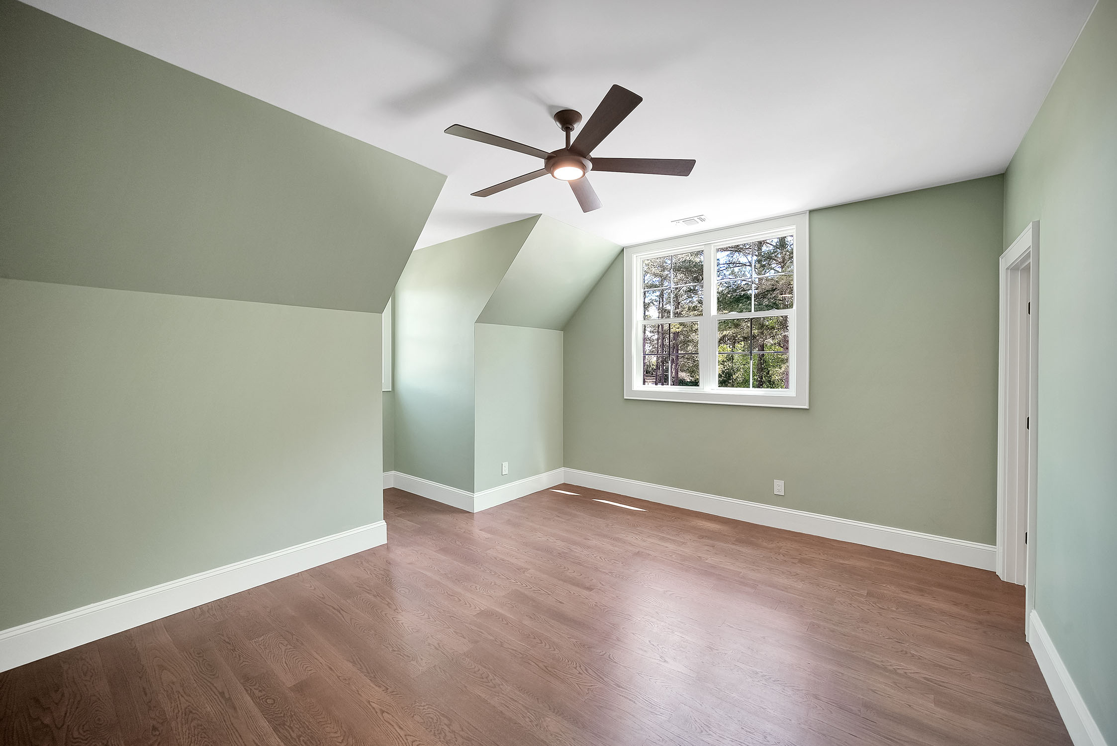 Empty green bedroom with sloped ceiling and fan
