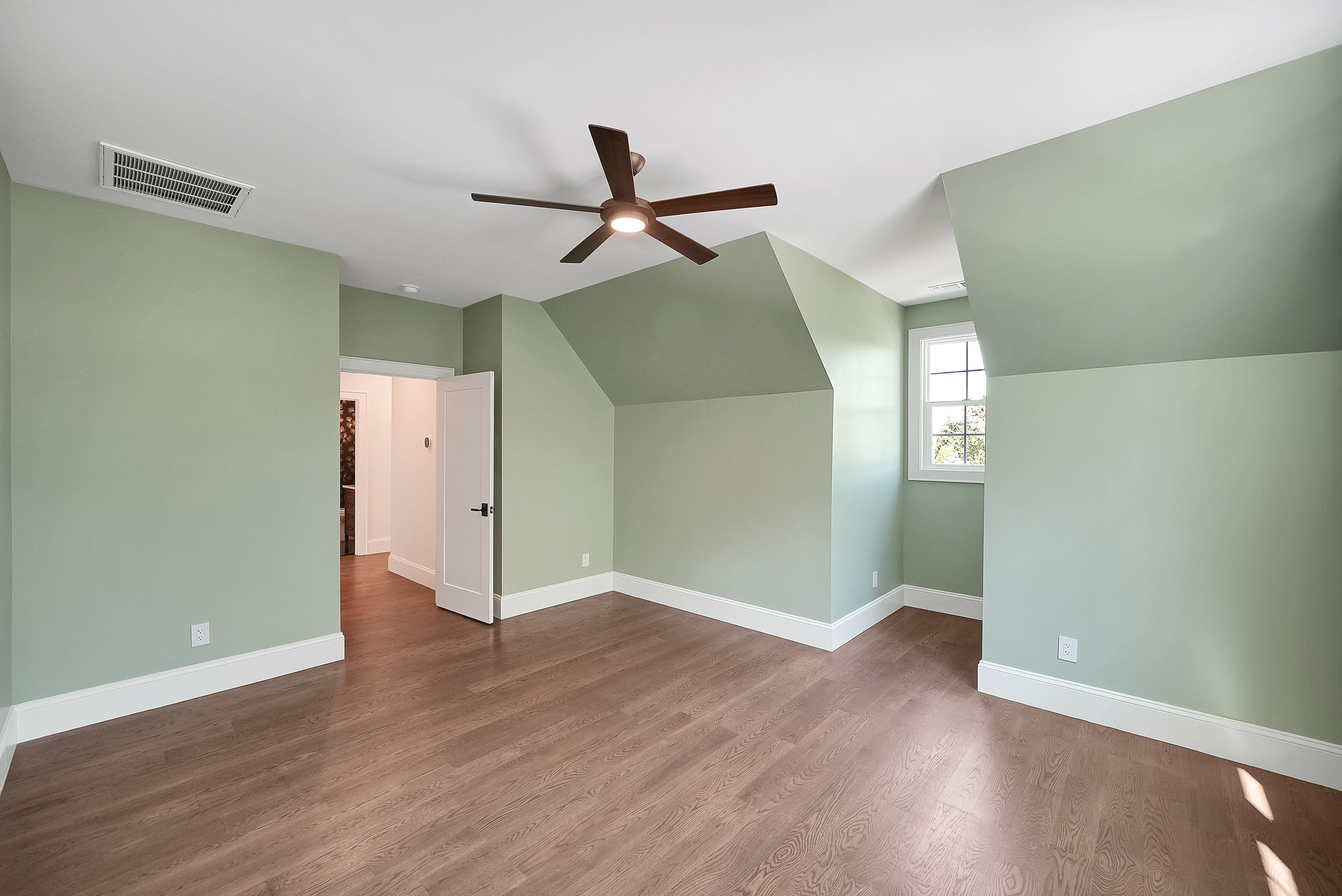Empty green bedroom with ceiling fan and hardwood floors