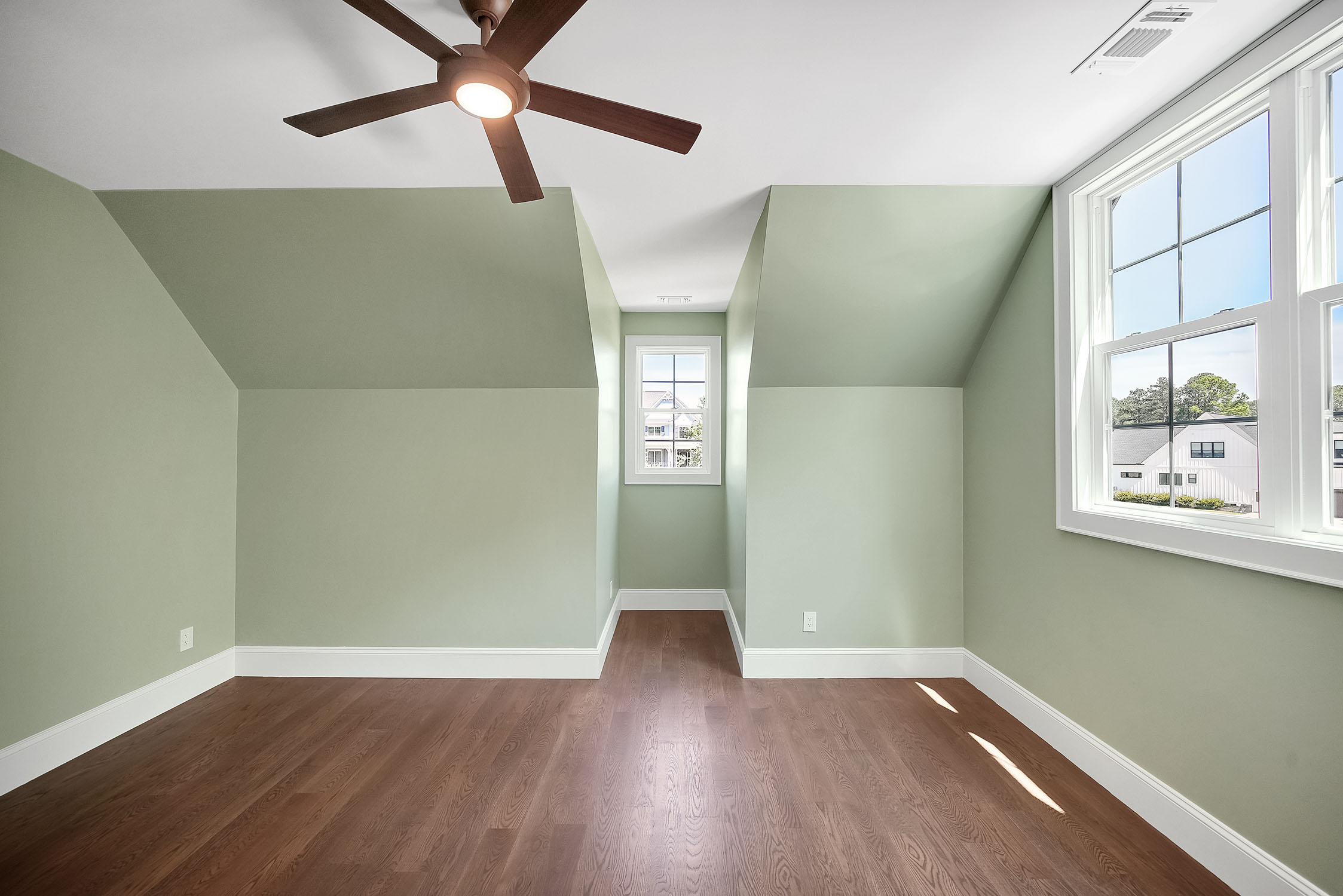Empty sage green room with sloped ceiling