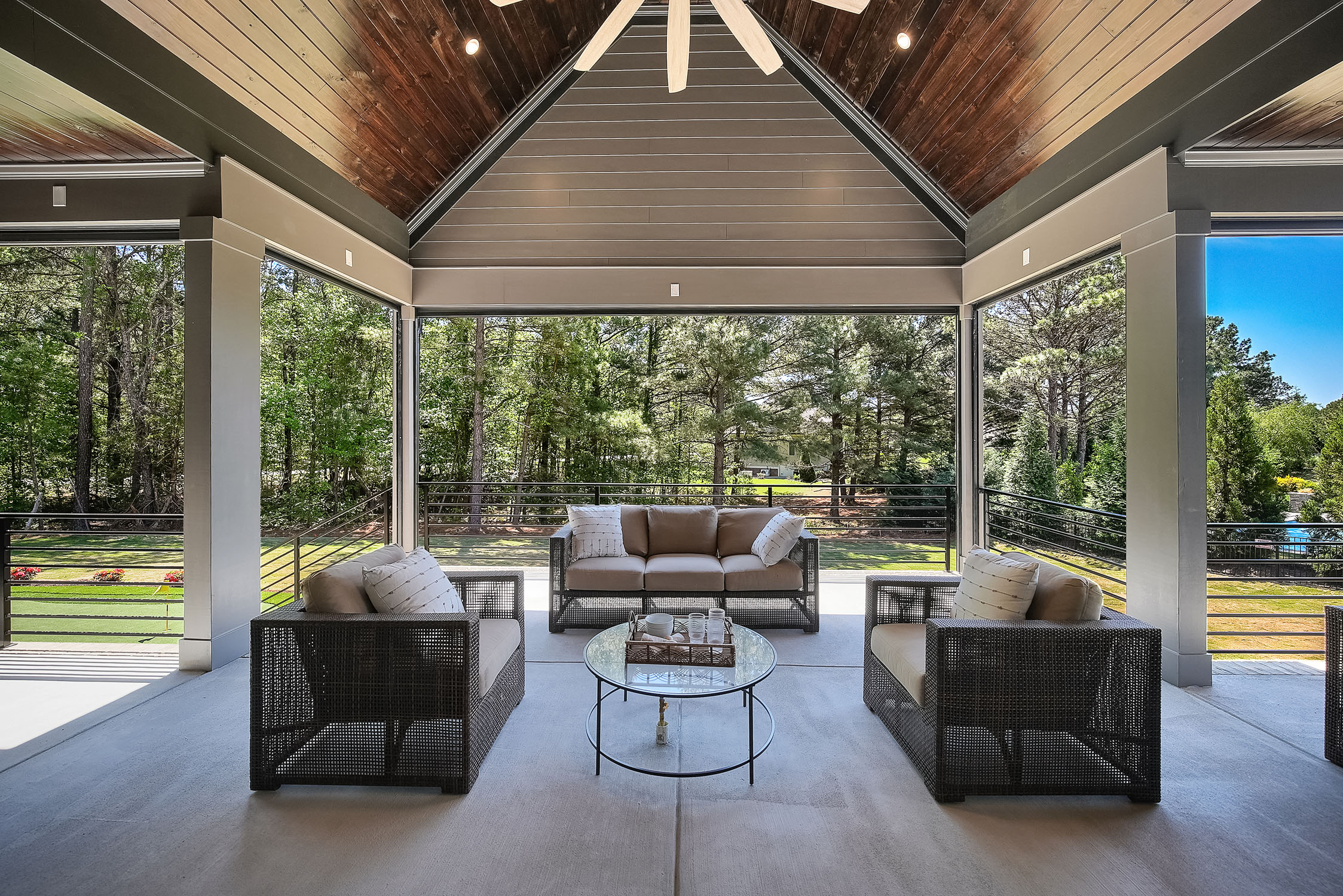 Covered patio with wicker seating and wooded view