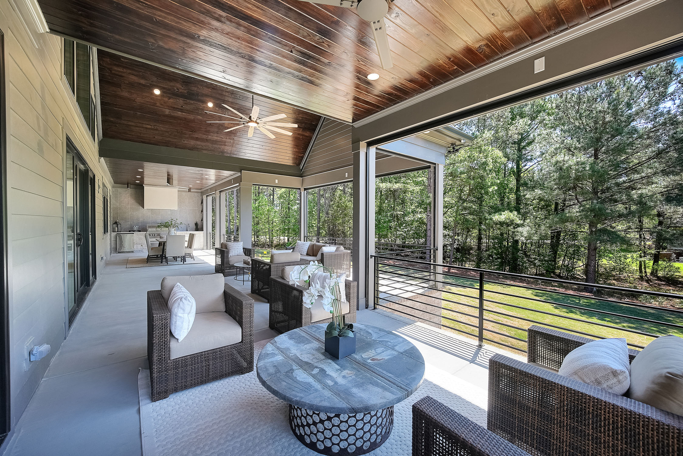 Covered patio with seating overlooking wooded backyard