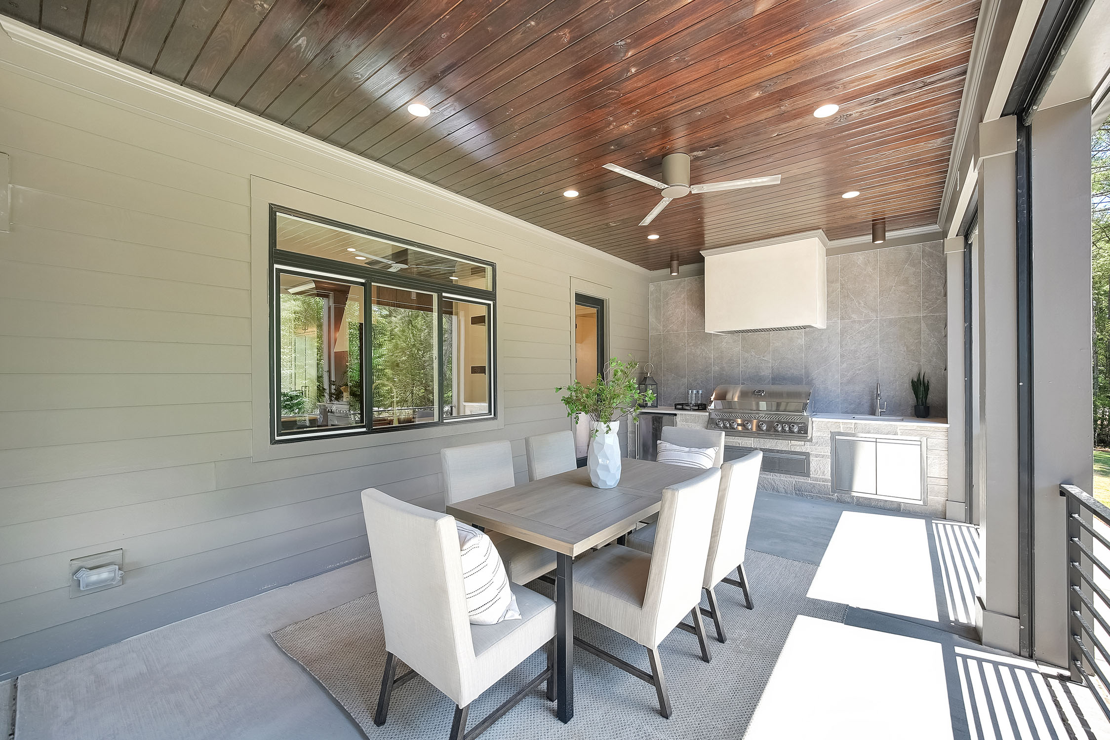 Covered outdoor patio with dining table and grill
