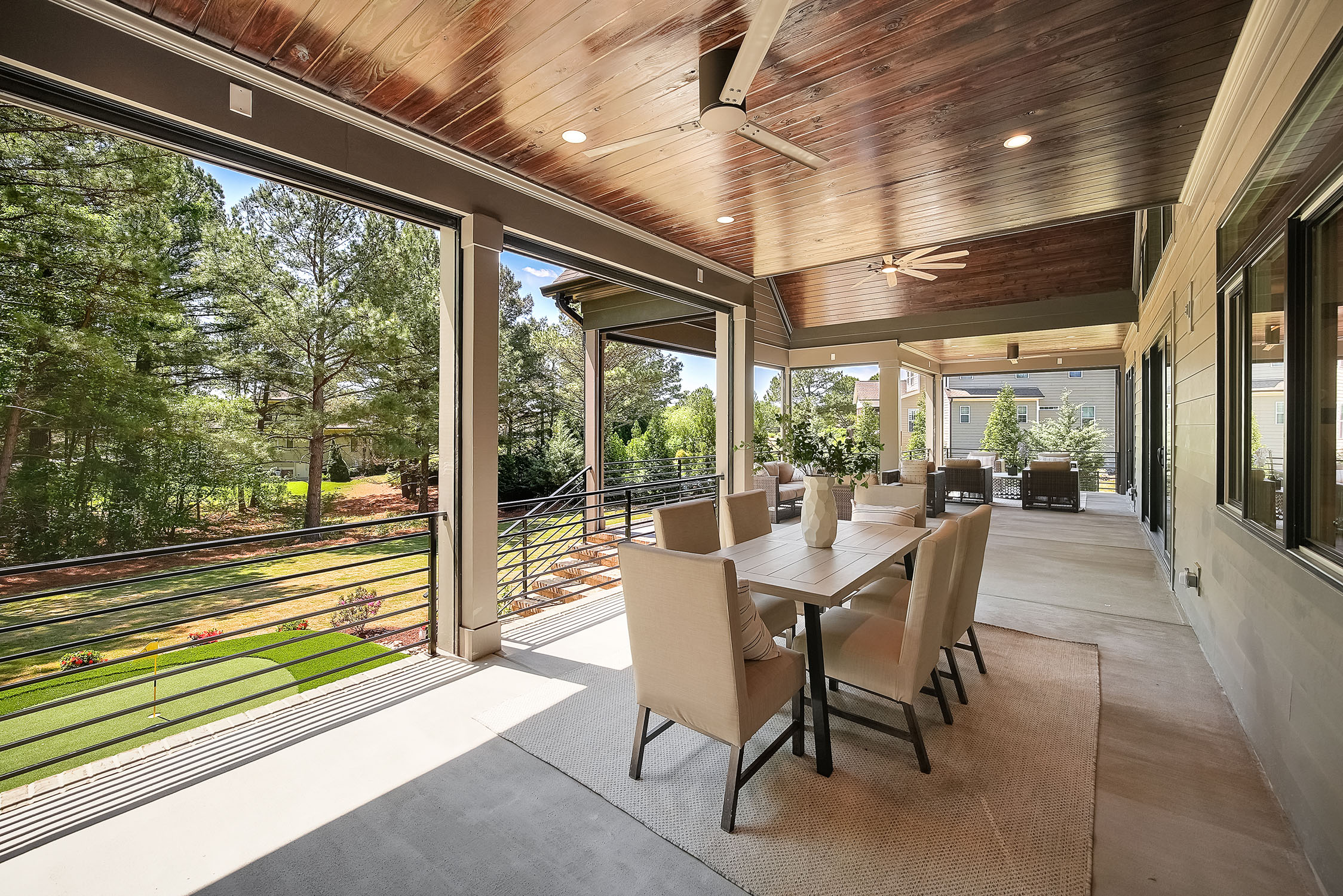 Covered outdoor patio with dining table and wooded view