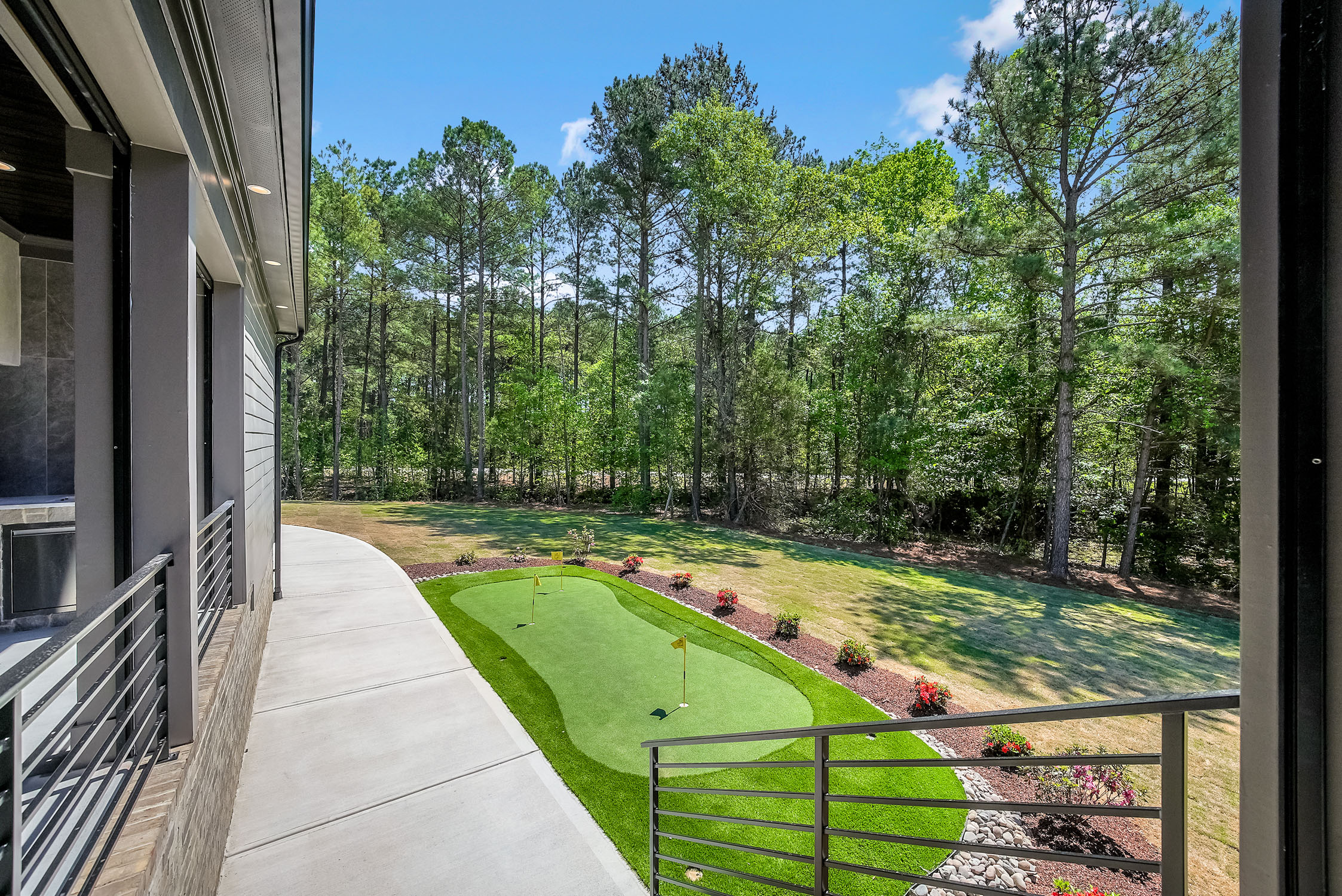Backyard putting green beside modern home and trees