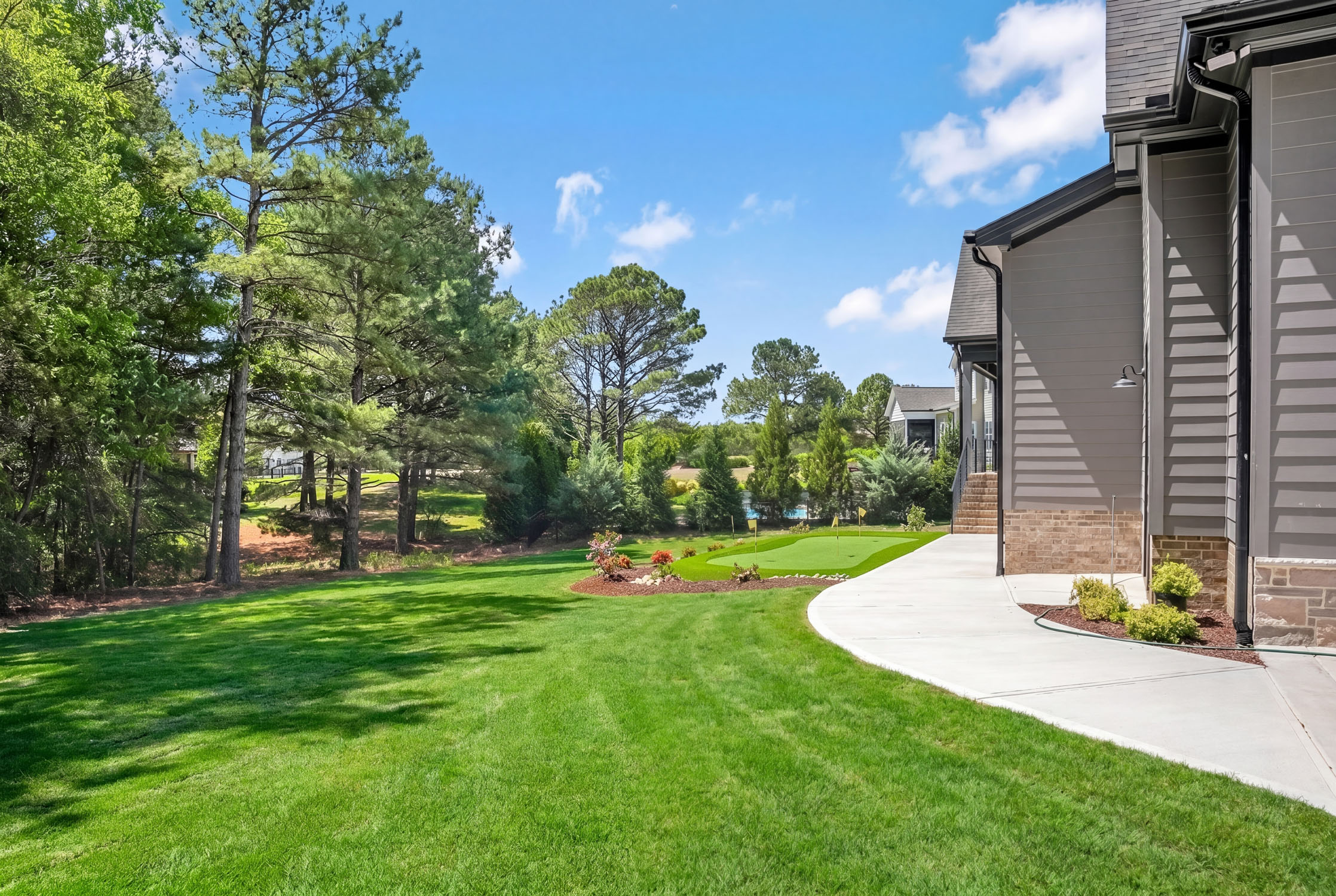 Modern home with backyard putting green and trees
