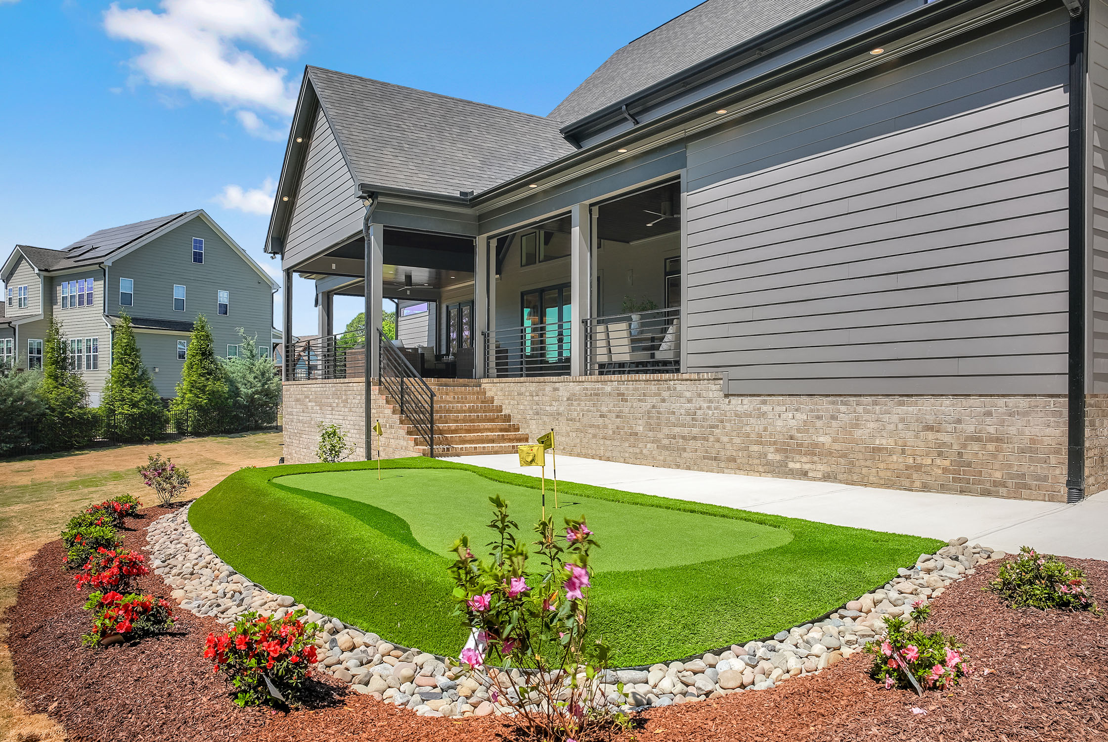 Modern backyard with putting green and covered patio