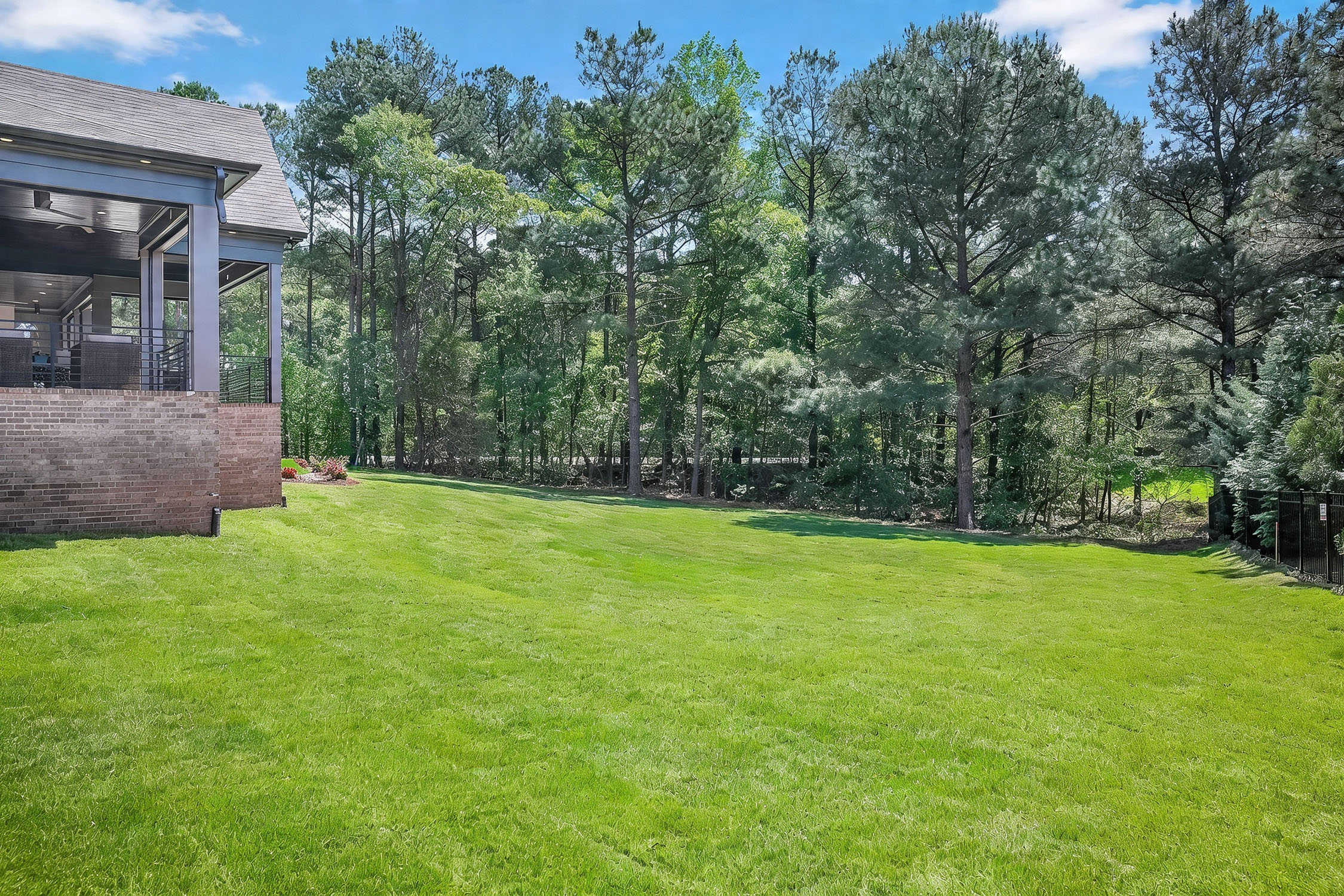 Spacious backyard with covered patio and tall trees
