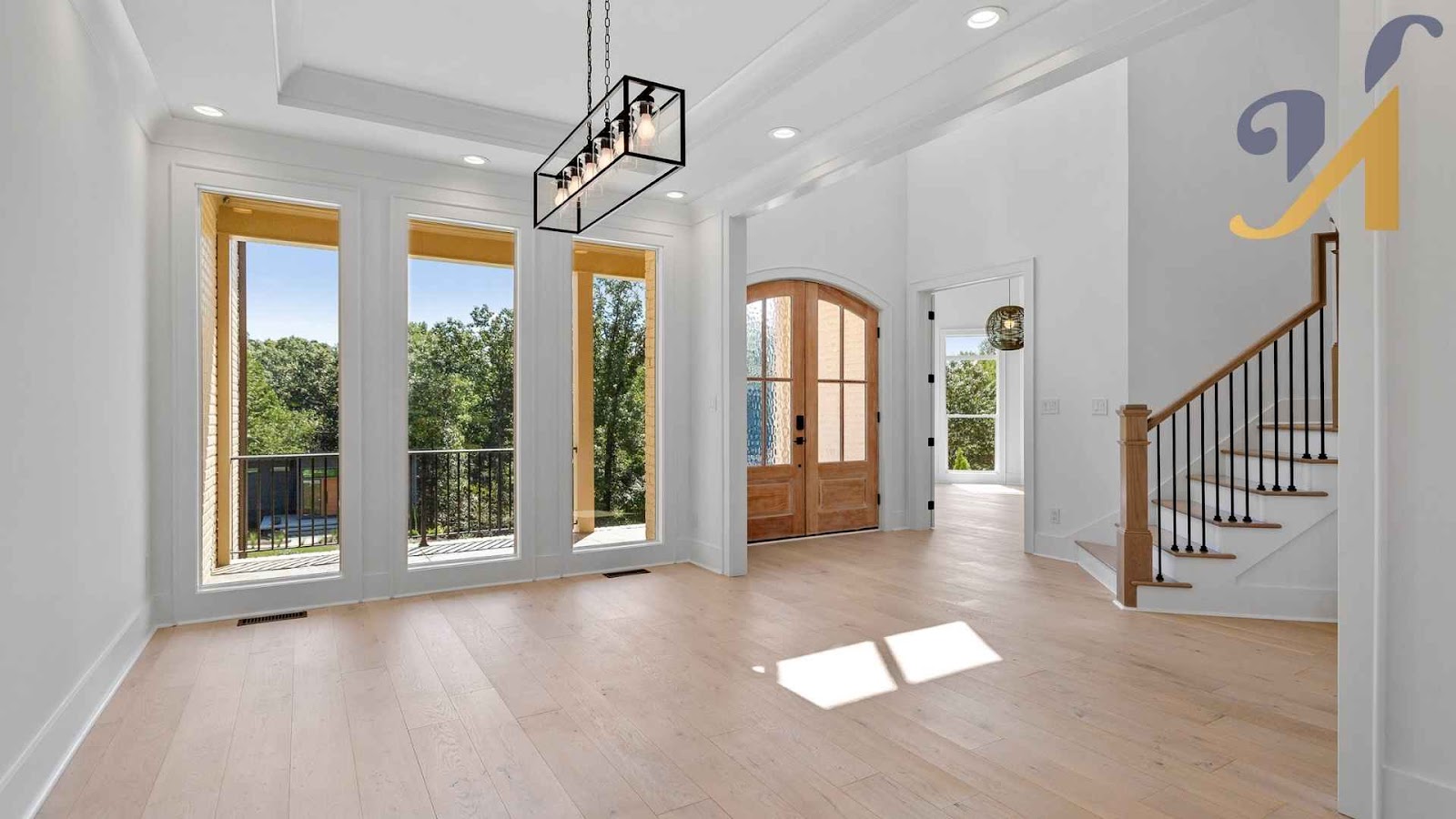Bright empty room with wooden floors and staircase.