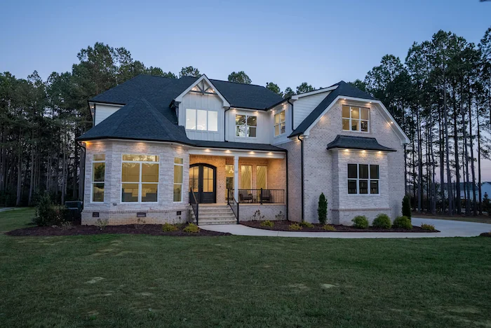 Modern two-story house with exterior lighting at dusk.