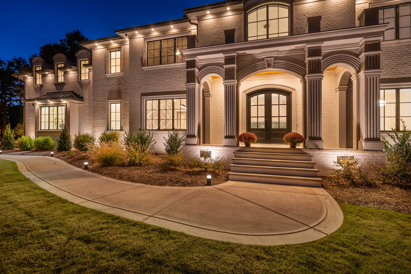 Elegant modern house exterior with nighttime lighting.