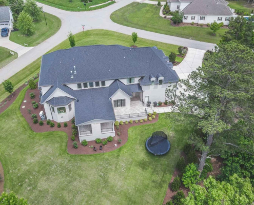 Aerial view of suburban house with yard and trees.