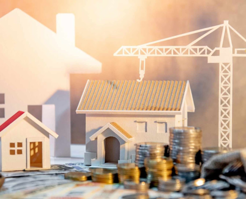 Models of houses with construction crane and coins.