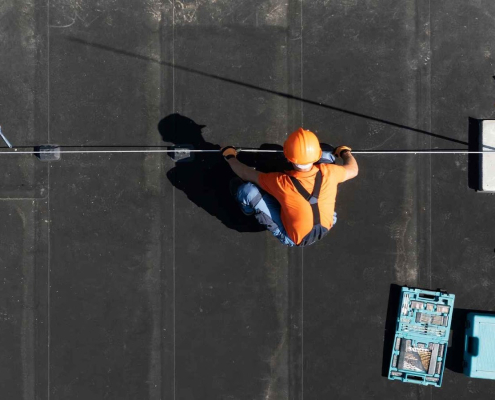 Rooftop worker with tools and safety gear.