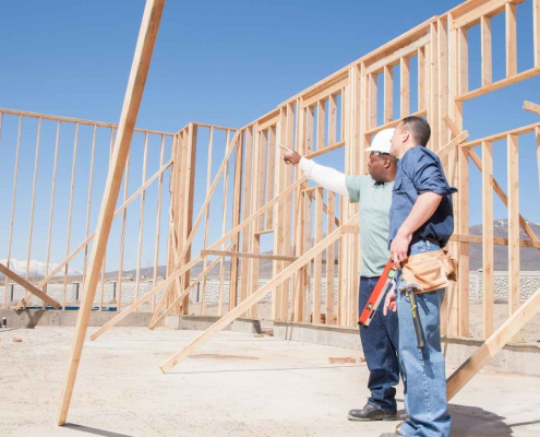 Construction workers examining wooden framework on site
