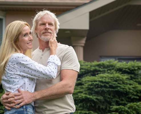 Elderly couple embracing outdoors near house