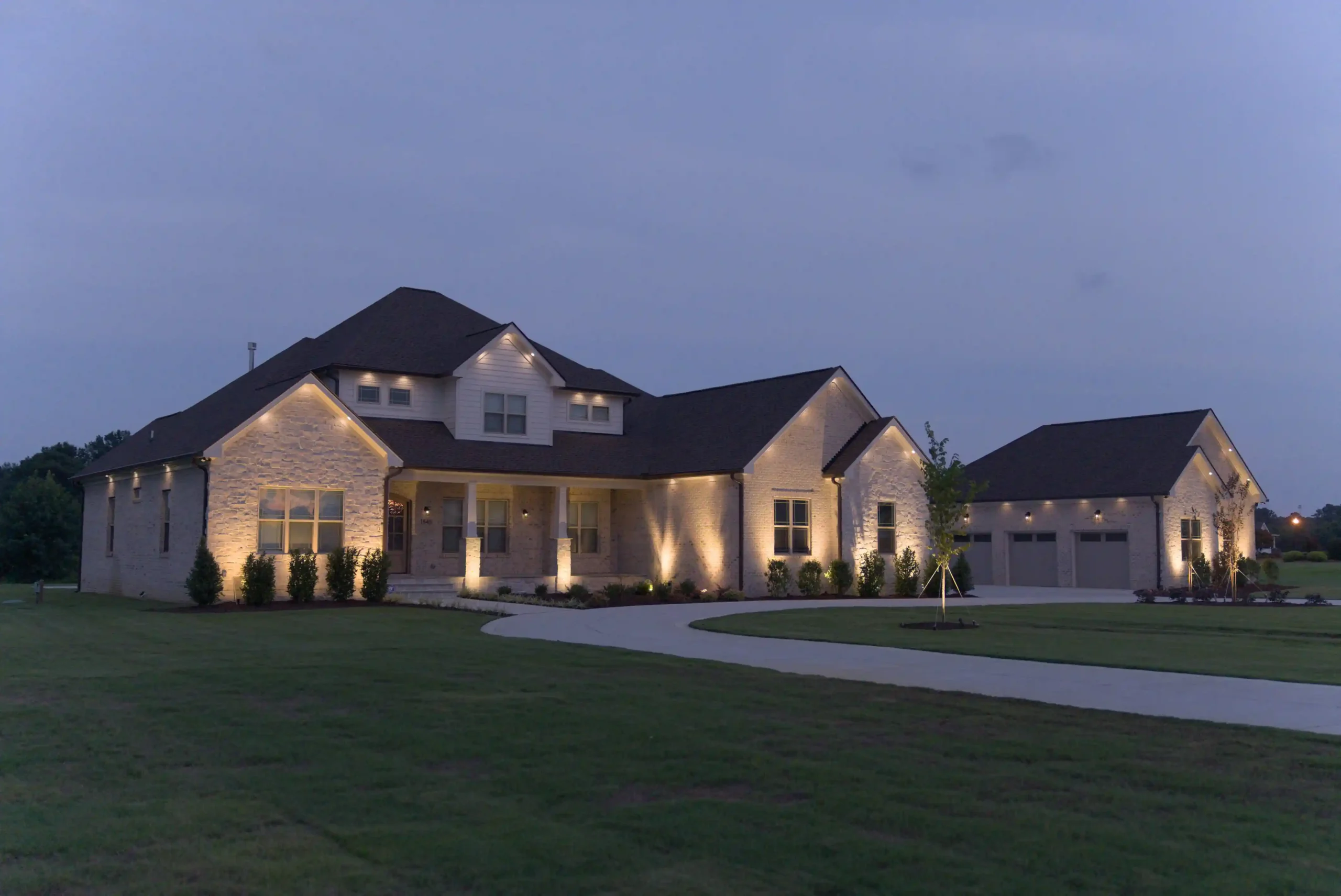 Illuminated suburban home with driveway at dusk.